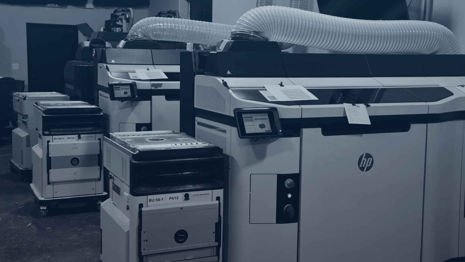 Several Impac Additive's HP-Jet-Fusion 5200 3D Printers with powder handlers next to them