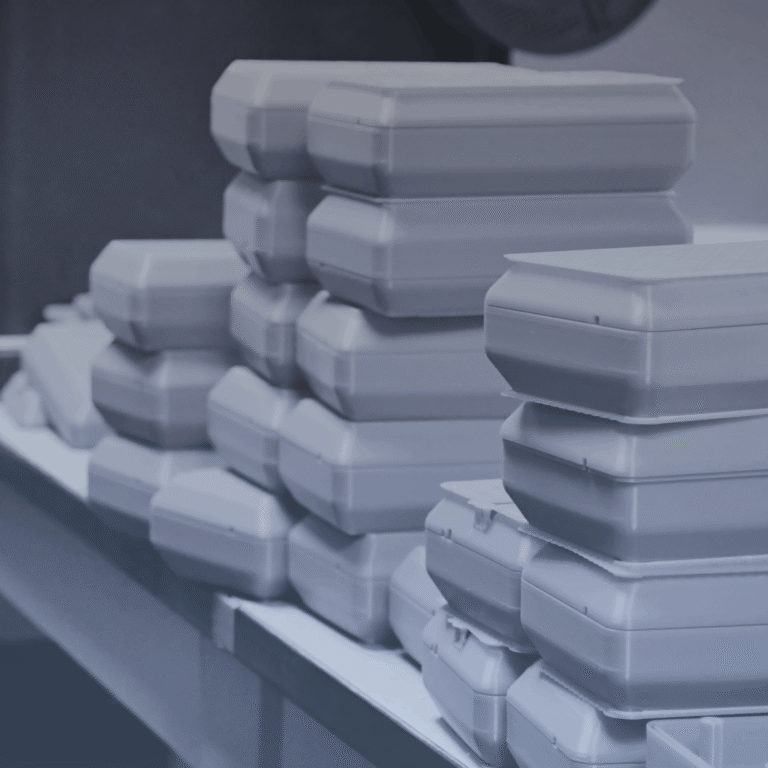 Samples of IA3D's End-Use Production: Stacks of 3D-printed boxes sit on a table