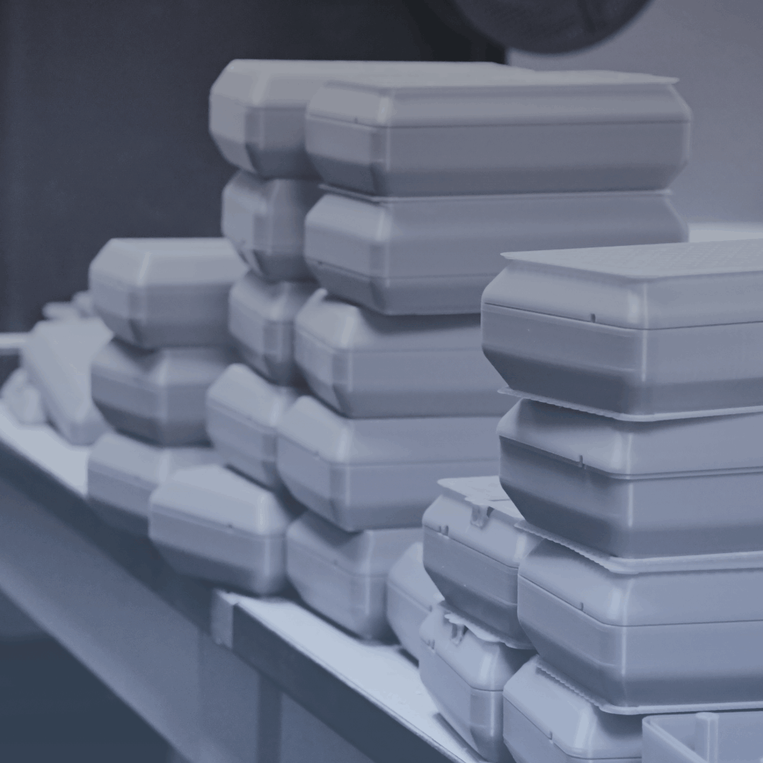 Samples of IA3D's End-Use Production: Stacks of 3D-printed boxes sit on a table