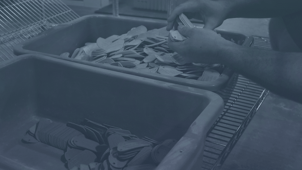 Pair of hands sorting a client's bridge manufacturing product, hundreds of small tabs in large plastic bins