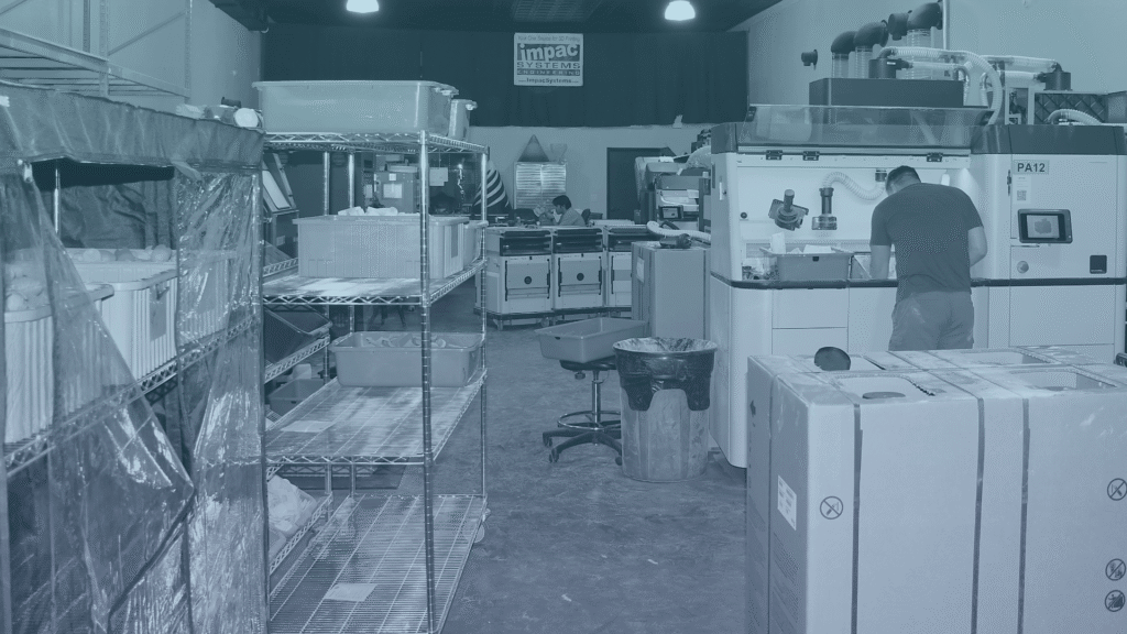 IA3D's print room, worker visible cleaning powder off parts