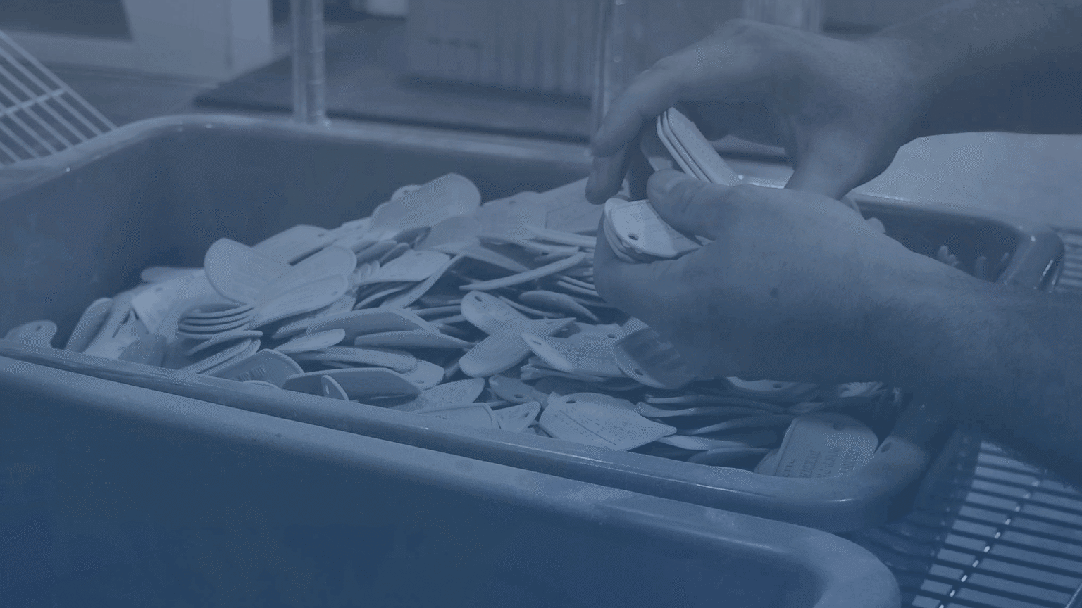 hands sorting 3D printed parts in a large plastic bin at Impac Additive 3D